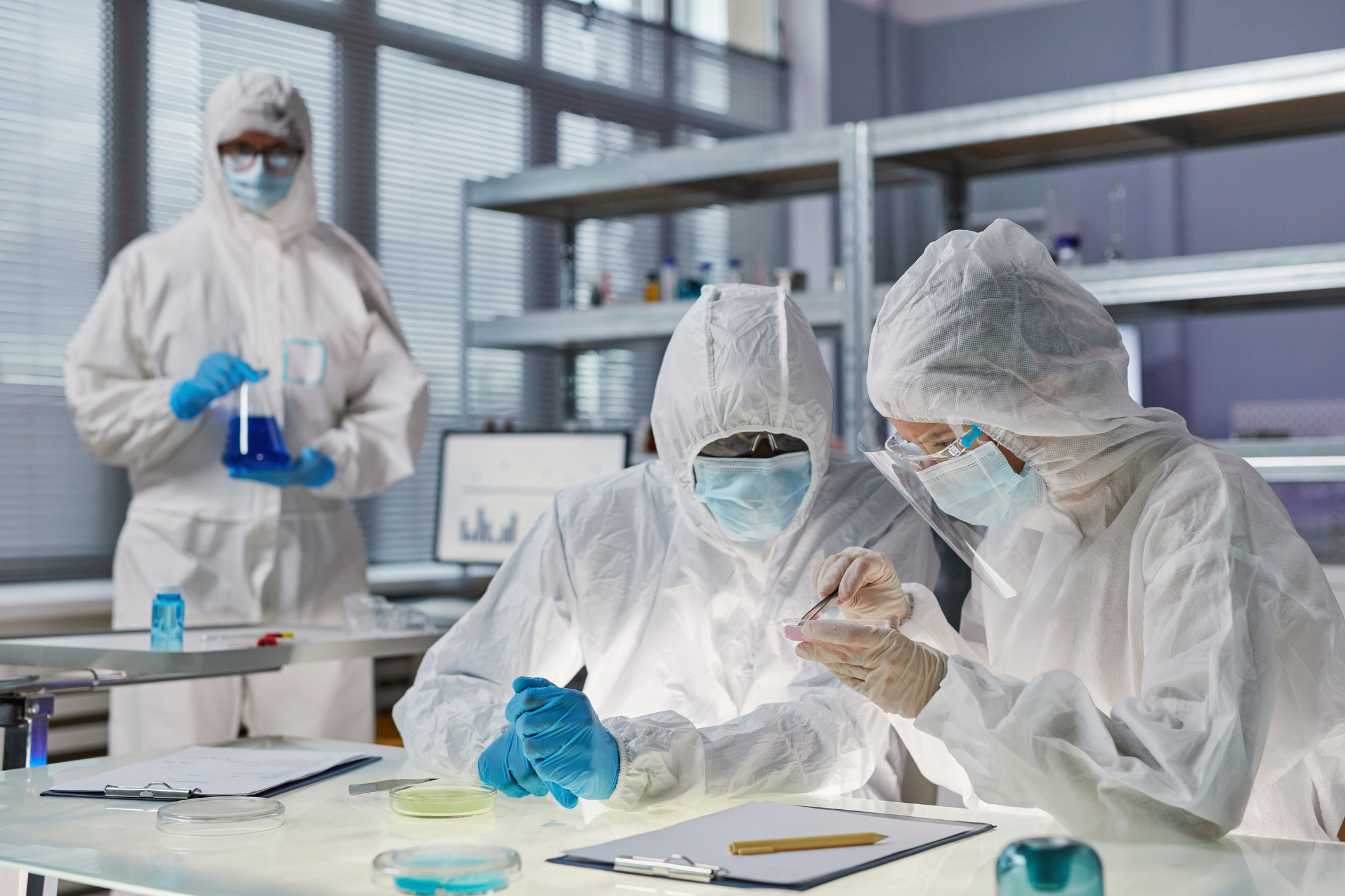 Group of people in protective suits working with chemicals in team in the laboratory